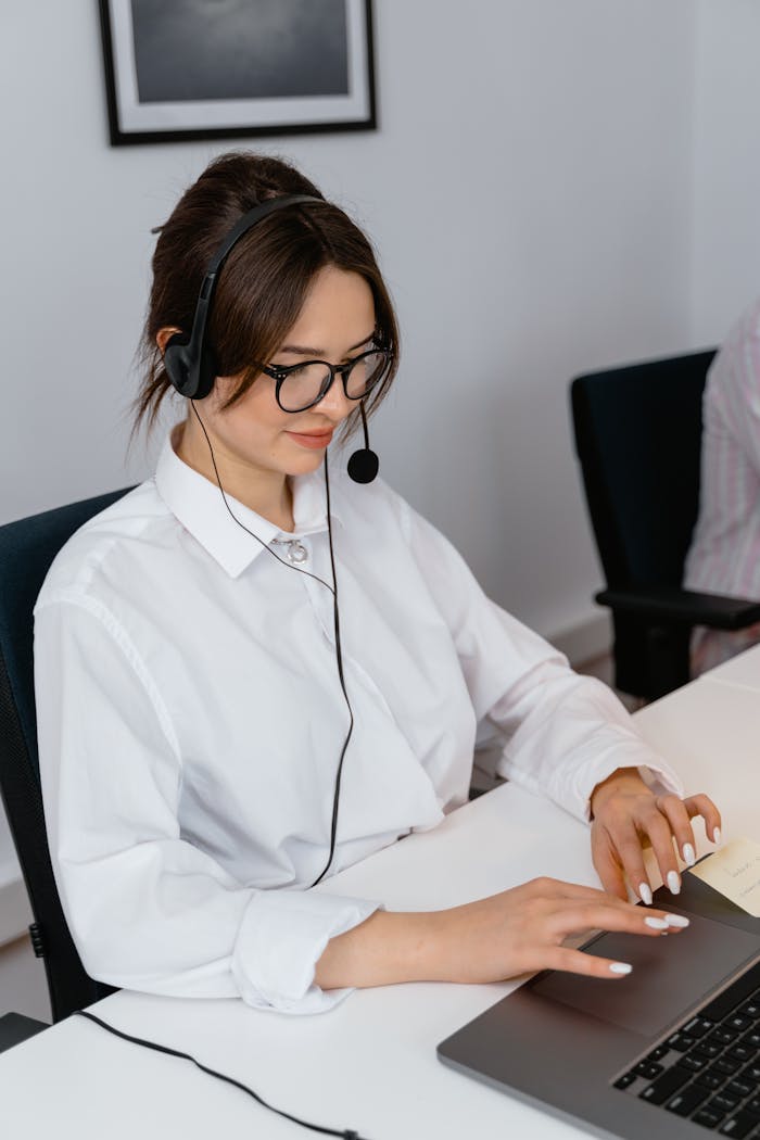 Cheerful woman in a call center using a laptop and headset for customer support.